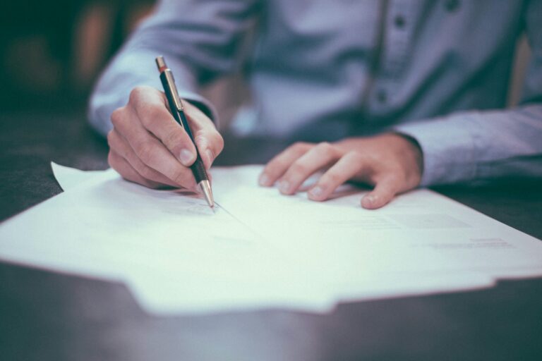 Manos escribiendo en una libreta de planeación financiera